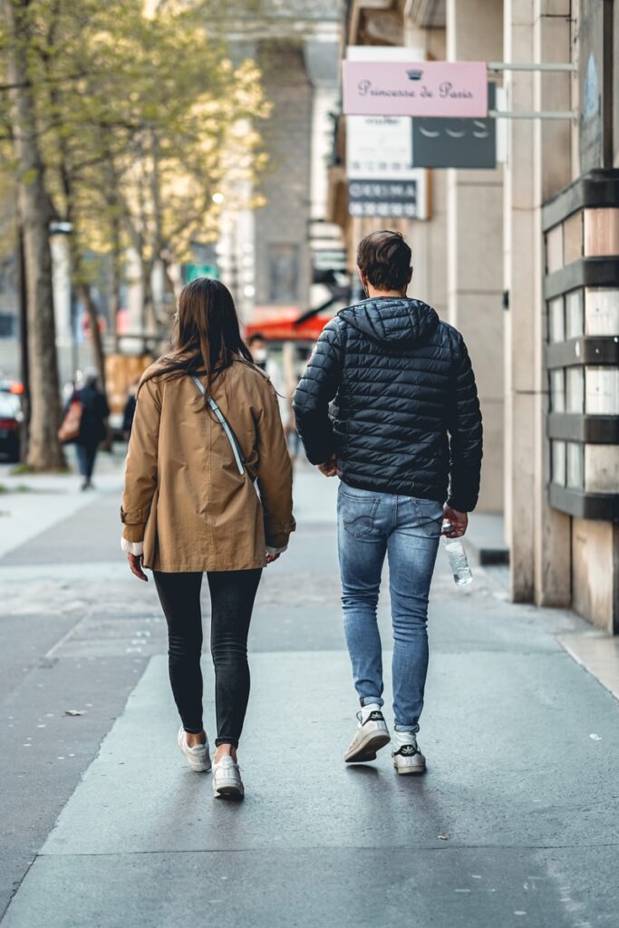 man and woman walking on sidewalk during daytime