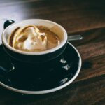 white and black ceramic mug filled with brown latte on round black ceramic saucer